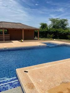 una grande piscina blu con tetto di paglia di Magnifica villa con giardino e piscina a Nianing