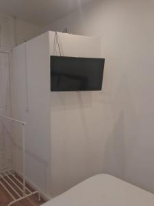 Elle comprend une télévision à écran plat suspendue sur un mur blanc. dans l'établissement Guesthouse Franco, à Porto