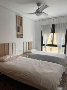 2 camas en un dormitorio con ventana en Edificio Columbretes, en Castellón de la Plana