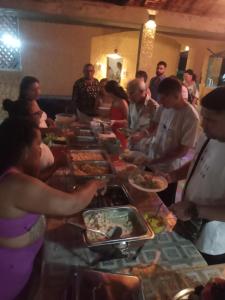 Hotel e Pousada Marajó في سالفاتيرا: مجموعة من الناس يجلسون حول طاولة طويلة يأكلون الطعام