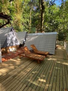 a wooden deck with a bench and a gazebo at Aquário Glamping in Abraão