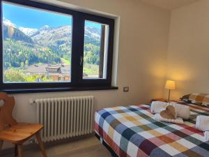 1 dormitorio con 2 camas y ventana grande en Il Rifugio dello Gnomo - Alpine Stay Apartments, en Panchia