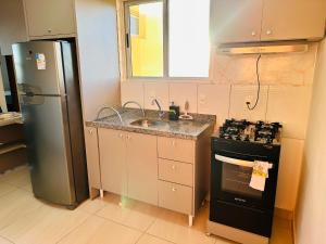a kitchen with a refrigerator and a sink and a stove at Apartamento Cuiabá - Luxxor Flat in Cuiabá