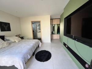 Périers-sur-le-Dan的住宿－Villa Verde — Jacuzzi, Moderne & Convivial，一间卧室配有一张床和一台平面电视