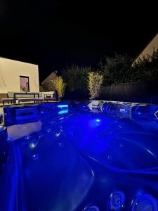 Périers-sur-le-Dan的住宿－Villa Verde — Jacuzzi, Moderne & Convivial，晚上在后院的蓝色热水浴池