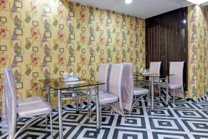 een eetkamer met tafels en stoelen en een gele muur bij Hotel Trishiv in kolkata