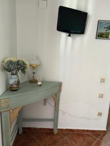 a green table with a tv on a wall at Casa Rural Tita Sacramento in Hornachos