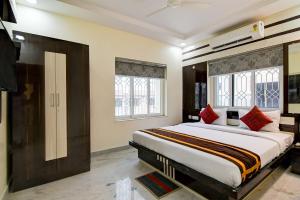 um quarto com uma cama grande e 2 janelas em Hotel Trishiv em kolkata