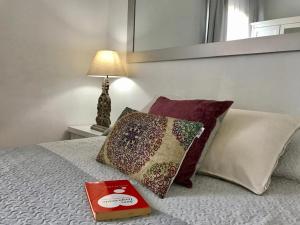 a book and pillows on a bed with a lamp at Borne rooms in Barcelona