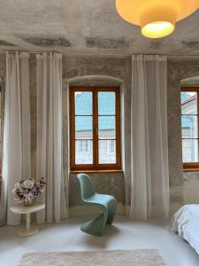 ein Schlafzimmer mit einem grünen Stuhl und Fenstern in der Unterkunft King ROSE by Rose Garden in Český Krumlov