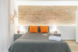a bedroom with a bed with orange pillows and a brick wall at Carretes 1 in Barcelona