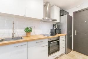 a kitchen with white cabinets and a stainless steel refrigerator at Carretes 1 in Barcelona