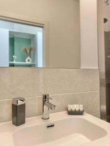 ein Waschbecken mit einem Wasserhahn und einem Spiegel in der Unterkunft Ihost apartment- Guarneri 24 in Mailand