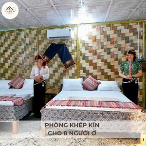 Homestay Minh Ngọc في Ban Hin Lom: امرأتين واقفتين في غرفة بسريرين