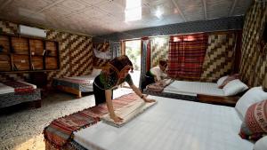 a woman making a bed in a room at Homestay Minh Ngọc in Ban Hin Lom
