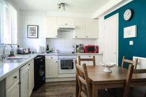 cocina con armarios blancos y mesa de madera en Modern Central Family-Home for 6, en Londres