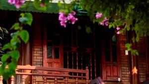a wooden bench in front of a house with pink flowers at Homestay Minh Ngọc in Ban Hin Lom