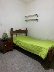 1 dormitorio con cama verde y mesita de noche en CASA DE LOS NONOS HOSPEDAJE en La Consulta
