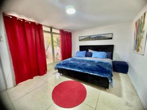 1 dormitorio con 1 cama con cortinas rojas y alfombra roja en Amplio apartamento renovado con 3 habitaciones, 3 baños, terrazas, Smart TV y wifi incluidos en Caracas