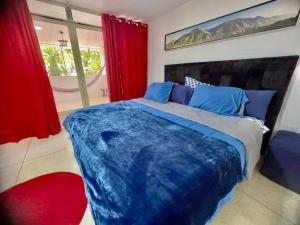 een slaapkamer met een groot blauw bed en rode gordijnen bij Amplio apartamento renovado con 3 habitaciones, 3 baños, terrazas, Smart TV y wifi incluidos in Caracas