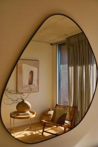 a mirror reflecting a room with a chair and a table at Aparthotel Oporto Anselmo in Porto