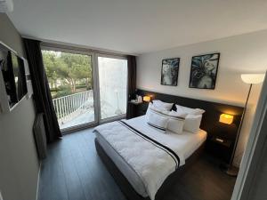 um quarto com uma cama e uma grande janela em Le Prose Hôtel em La Grande-Motte