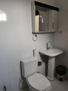 La salle de bains blanche est pourvue de toilettes et d'un lavabo. dans l'établissement CasaCozy, à Boa Vista