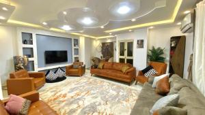Il comprend un salon avec des canapés et une télévision à écran plat. dans l'établissement شقة فندقية للإيجار في زهراء المعادي, au Caire
