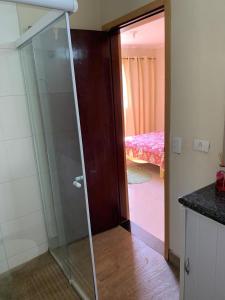 a glass shower door in a room with a bedroom at Pousada Villa Argos Guesthouse in Piracicaba