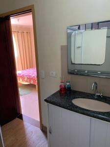 a bathroom with a sink and a mirror and a bedroom at Pousada Villa Argos Guesthouse in Piracicaba
