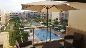 - une vue sur la piscine depuis un balcon avec un parasol dans l'établissement LE GRANd BLEU - ONLY FAMILIES, à Sidi Bouqnadel