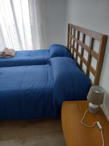 - un lit avec une couette bleue à côté d'une table dans l'établissement Casa turistica Santa Lucia 25, à Regalbuto