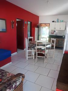 Apartamento a Beira Mar في جاغوارونا: غرفة مع طاولة وكراسي وجدار احمر