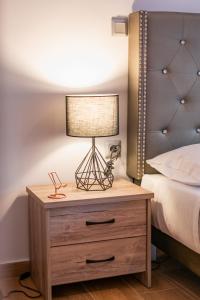 una lámpara en una mesita de noche junto a una cama en Lux Modern Apt Ανακαινισμένο διαμέρισμα 150m από την πλαζ 'ΈΔΕΜ', en Atenas