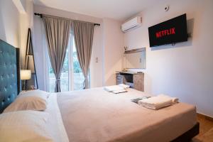 1 dormitorio con 1 cama grande y TV en la pared en Lux Modern Apt Ανακαινισμένο διαμέρισμα 150m από την πλαζ 'ΈΔΕΜ', en Atenas