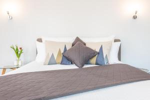 una cama con muchas almohadas encima en Apartamenty Tespis - Francuska Atal Park en Katowice