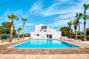 a villa with a swimming pool and palm trees at Acogedor Duplex en Ciutadella-Playa Santandria in Cala Santandria
