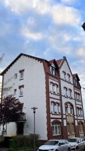 un edificio blanco y rojo con coches estacionados frente a él en Wohnung in Kirchditmold en Kassel