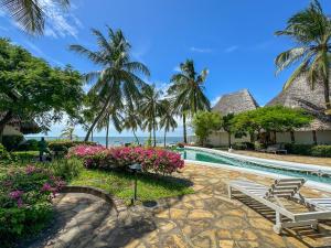 un complejo con piscina y palmeras en Kaleb's Beachfront Villa, en Malindi