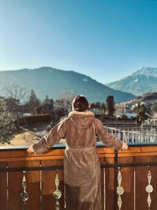 une personne debout sur un balcon donnant sur les montagnes dans l'établissement Residence Neuhäuslhof, à Merano