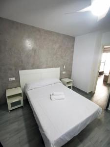 sypialnia z dużym białym łóżkiem i dwoma stołami w obiekcie Barbate Alojamientos Turísticos w mieście Barbate