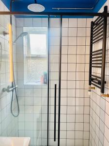 La salle de bains est pourvue de carrelage blanc, d'une douche et d'une fenêtre. dans l'établissement S29 Apartment, à Reykjavik