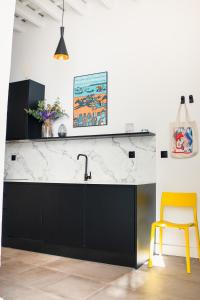 a kitchen with a black and white counter and a yellow stool at Casa Miguel - Apartamento 1 in Sanlúcar de Barrameda