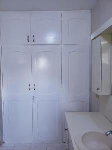 La salle de bains blanche est pourvue d'un lavabo et de placards blancs. dans l'établissement Cozy Apartment Greenwood, à Montego Bay