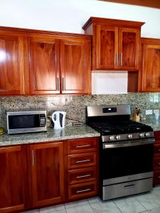 - une cuisine avec des placards en bois, une cuisinière et un four micro-ondes dans l'établissement Cozy Apartment Greenwood, à Montego Bay