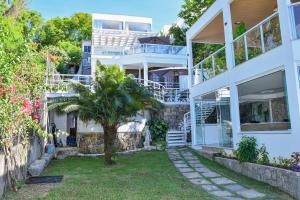 Biały dom z palmą na podwórku w obiekcie Casa Oásis do Moreno 6 w mieście Vila Velha