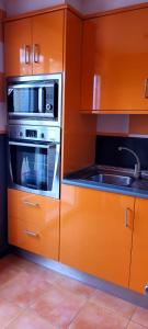 eine Küche mit orangefarbenen Schränken und einer Mikrowelle in der Unterkunft Apartamento Ideal para Grandes Familias in Miramar