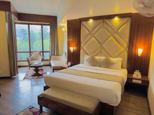 a bedroom with a large bed and a large window at River Grand View Resort and SPA Manali - A River side Property in Manāli