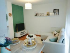 a living room with a white couch and a tv at La Berrea Cabañaquinta in Aller