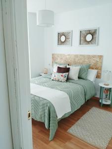 a bedroom with a bed with green and white sheets at La Berrea Cabañaquinta in Aller
